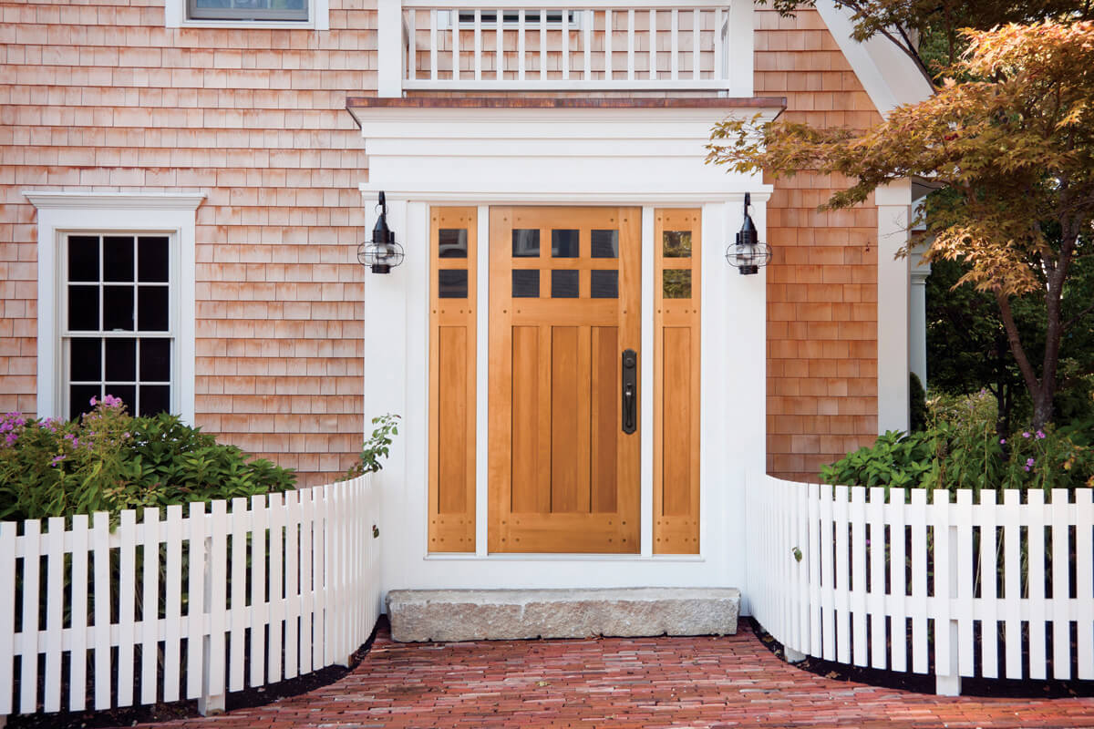 wood entry door with dark handle and white fence